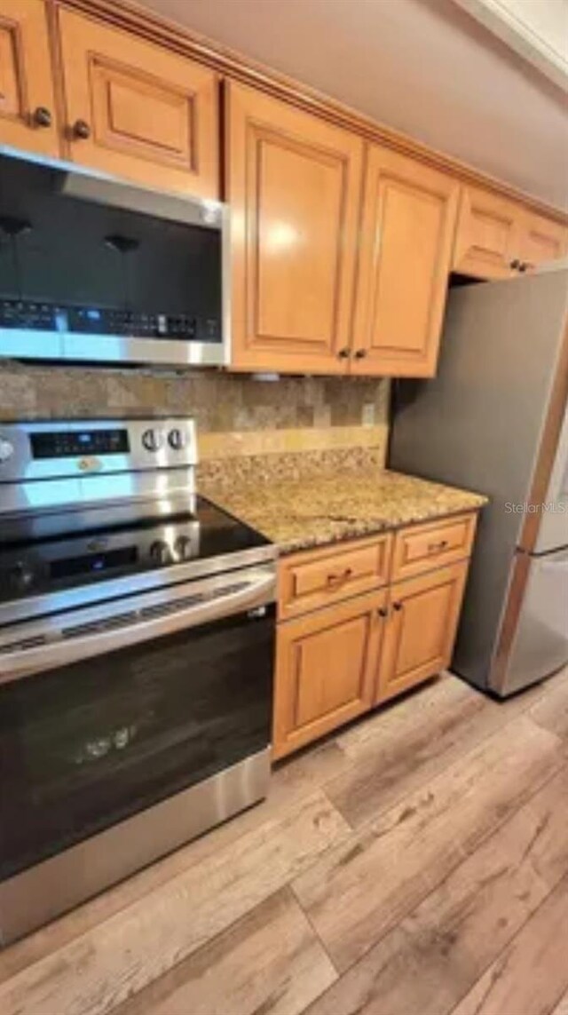 625 Duchess Blvd, Dunedin, FL 34698 - kitchen with stainless steel appliances, light wood-style flooring, light stone countertops, and tasteful backsplash