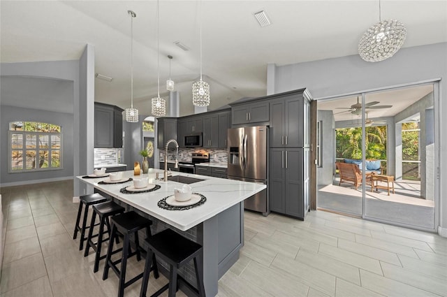 kitchen with pendant lighting, sink, stainless steel appliances, and an island with sink