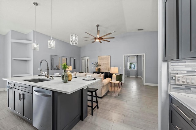 kitchen featuring sink, hanging light fixtures, a kitchen island with sink, ceiling fan, and light stone counters