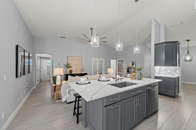 kitchen featuring gray cabinets, dishwasher, sink, a kitchen breakfast bar, and a center island with sink