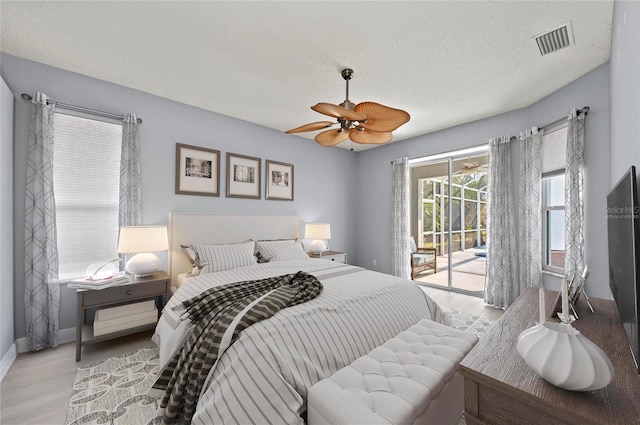 bedroom with ceiling fan, light wood-type flooring, a textured ceiling, and access to outside