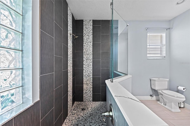 bathroom featuring a tile shower, a textured ceiling, and toilet