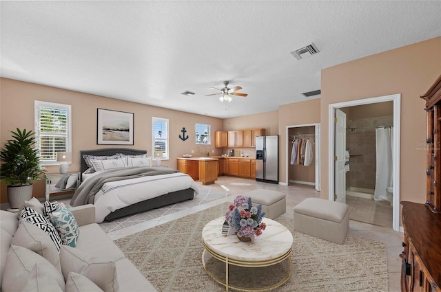 tiled bedroom featuring ensuite bathroom, stainless steel refrigerator with ice dispenser, a textured ceiling, a spacious closet, and a closet