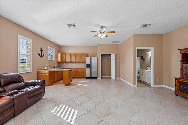 tiled living room with ceiling fan and a textured ceiling