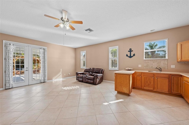 interior space featuring french doors, a healthy amount of sunlight, a textured ceiling, and light tile patterned floors