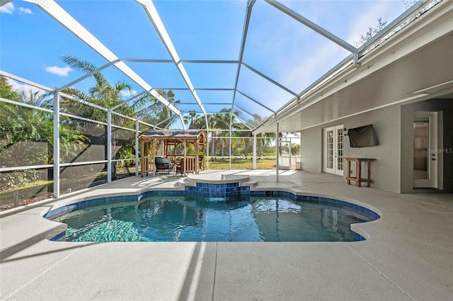 view of pool with pool water feature, glass enclosure, a gazebo, a patio area, and french doors