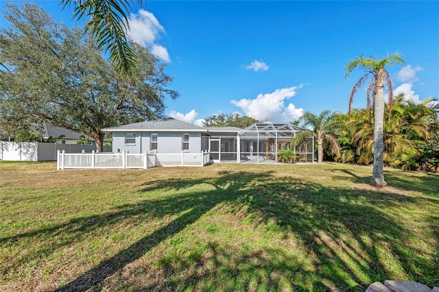 rear view of property featuring a lanai and a lawn