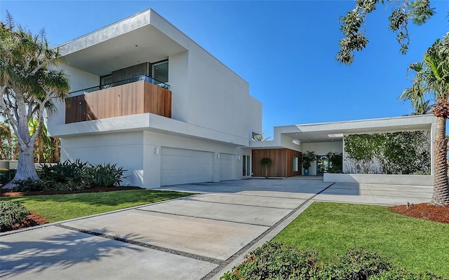 contemporary house with a garage, a front lawn, and a balcony