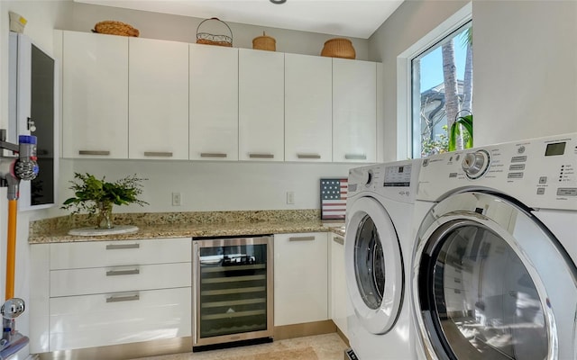 clothes washing area with wine cooler, washing machine and clothes dryer, and bar