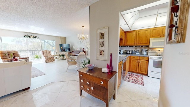 kitchen with pendant lighting, white appliances, a notable chandelier, light tile patterned floors, and a textured ceiling