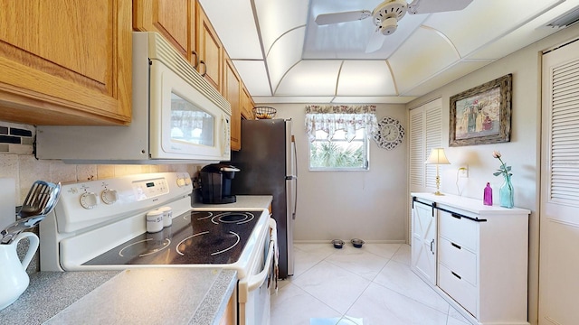 kitchen with a raised ceiling, ceiling fan, light tile patterned floors, and white appliances