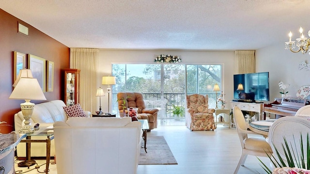 living room featuring a notable chandelier, a textured ceiling, and light hardwood / wood-style flooring