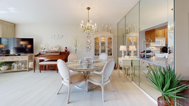 dining room with an inviting chandelier, light hardwood / wood-style flooring, and a textured ceiling