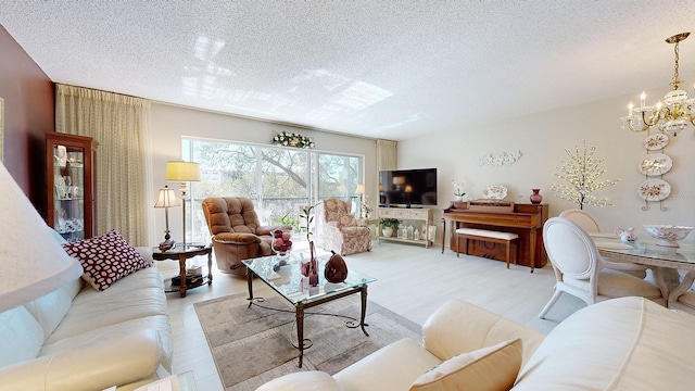 living room featuring a chandelier, light hardwood / wood-style floors, and a textured ceiling