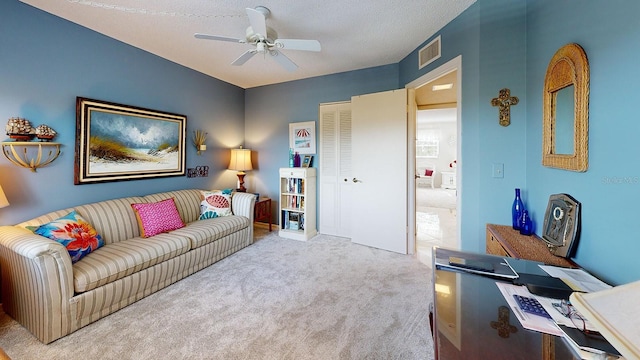 carpeted living room with a textured ceiling and ceiling fan