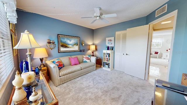 carpeted living room featuring a textured ceiling and ceiling fan