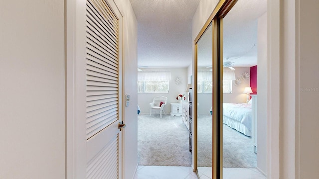 hall with light carpet and a textured ceiling