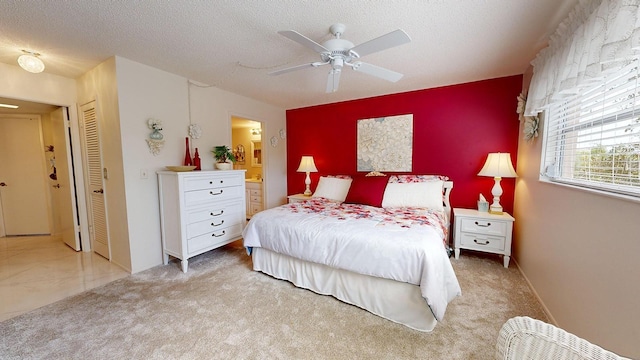 bedroom featuring ceiling fan, connected bathroom, light carpet, and a textured ceiling