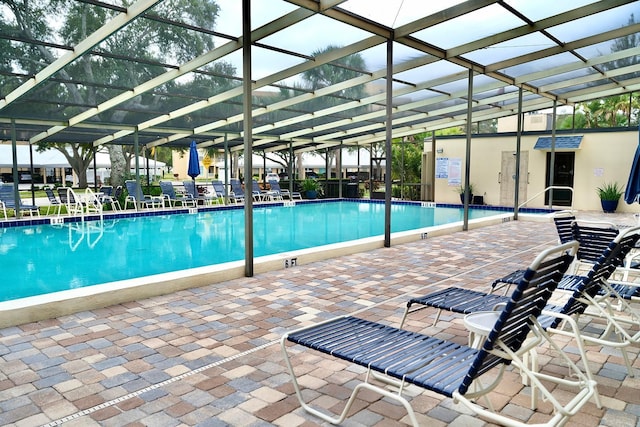 view of swimming pool with a patio area and glass enclosure