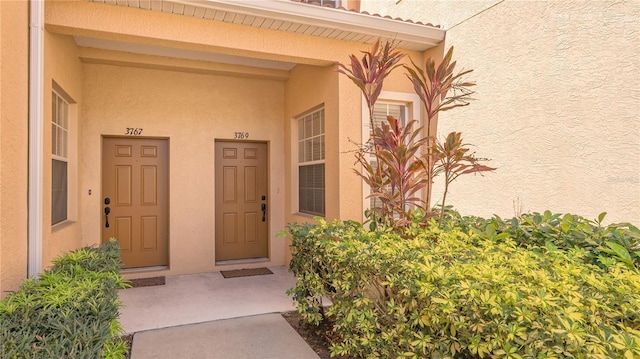 view of exterior entry featuring a tiled roof and stucco siding