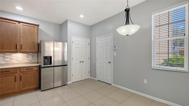 kitchen featuring light countertops, brown cabinetry, decorative backsplash, and stainless steel fridge with ice dispenser