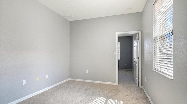 unfurnished room featuring carpet floors, plenty of natural light, and baseboards