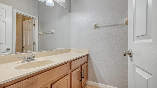 bathroom featuring a textured wall, vanity, and baseboards