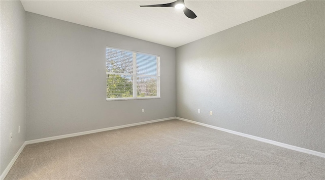 spare room featuring carpet, baseboards, ceiling fan, and a textured wall