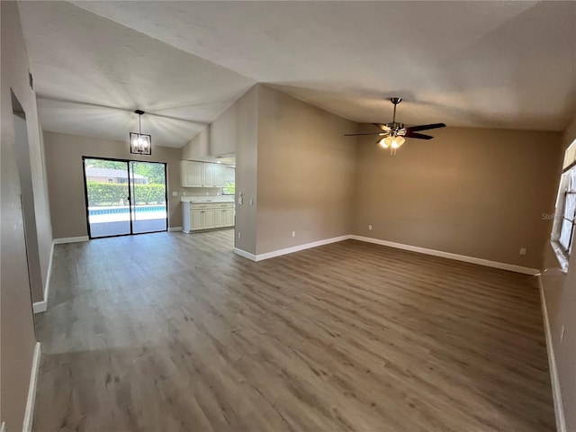 unfurnished living room with hardwood / wood-style flooring, vaulted ceiling, and ceiling fan with notable chandelier