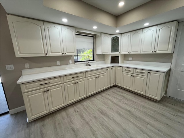 kitchen featuring sink, light hardwood / wood-style flooring, and white cabinets