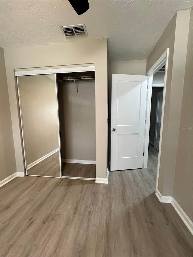 unfurnished bedroom featuring hardwood / wood-style flooring, a textured ceiling, and a closet