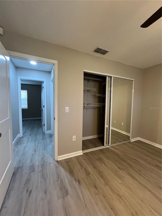 unfurnished bedroom with ceiling fan, hardwood / wood-style floors, and a closet