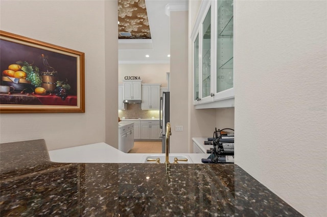 interior space featuring tasteful backsplash, white cabinets, stainless steel fridge, ornamental molding, and sink