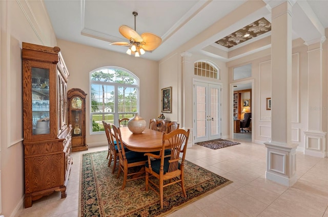 dining room featuring french doors, light tile patterned flooring, a raised ceiling, ornamental molding, and ornate columns