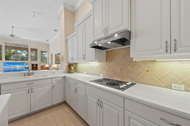 kitchen featuring white cabinets, decorative backsplash, crown molding, sink, and electric cooktop