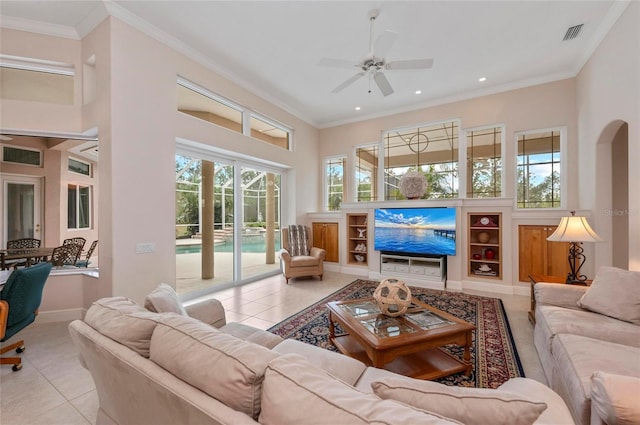 living room with a towering ceiling, crown molding, ceiling fan, and light tile patterned floors