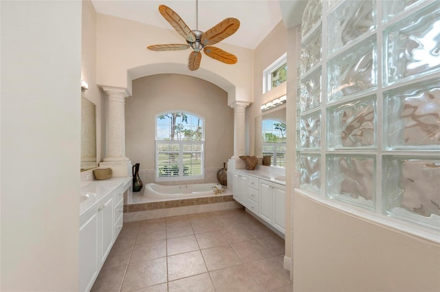 bathroom featuring tile patterned floors, ornate columns, ceiling fan, vanity, and a relaxing tiled tub