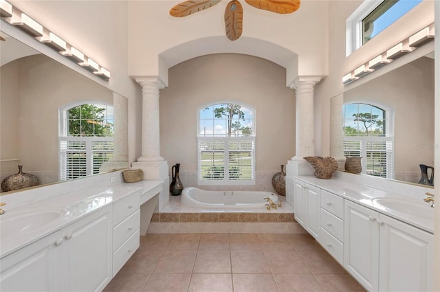 bathroom featuring vanity, tiled tub, decorative columns, and a healthy amount of sunlight