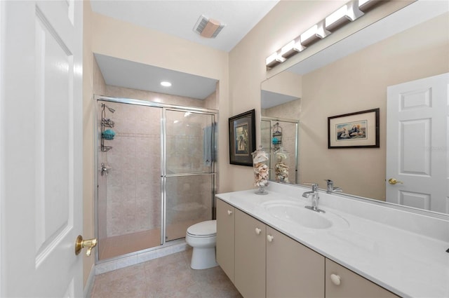 bathroom featuring toilet, tile patterned floors, vanity, and a shower with door