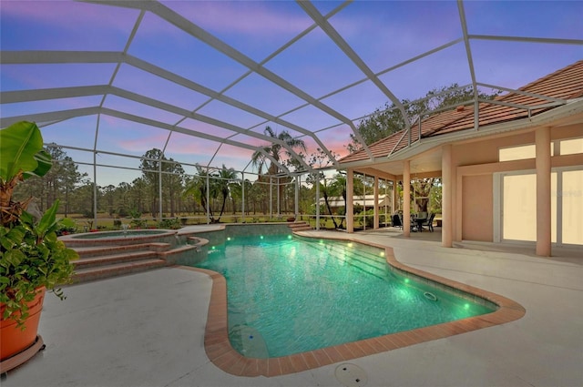 pool at dusk with an in ground hot tub, glass enclosure, and a patio