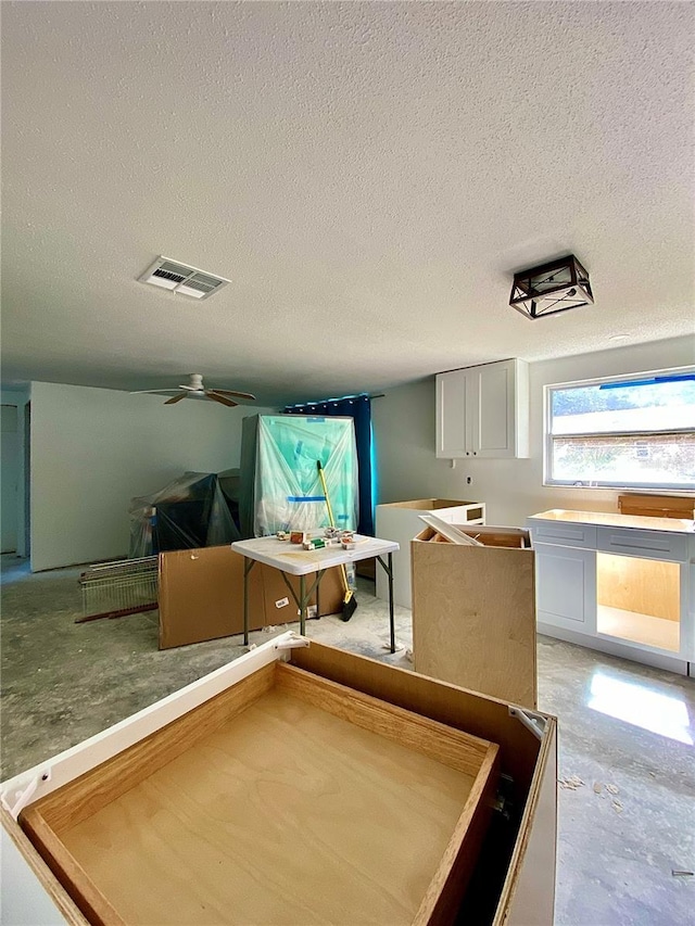 interior space with ceiling fan and a textured ceiling