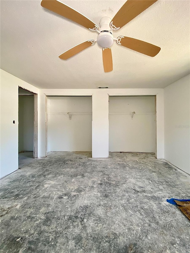 unfurnished bedroom featuring multiple closets, ceiling fan, and a textured ceiling