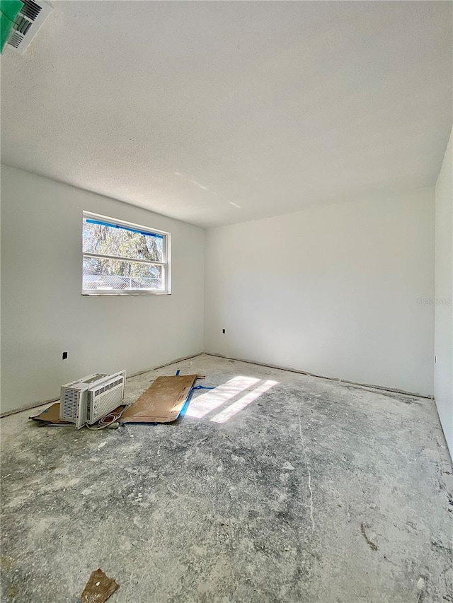 empty room with a wall mounted AC and a textured ceiling