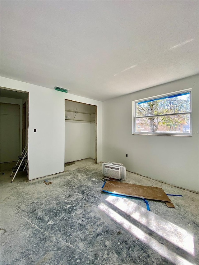 unfurnished bedroom featuring an AC wall unit and a closet