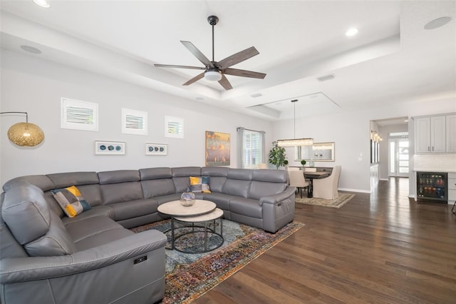 living room with ceiling fan, beverage cooler, dark hardwood / wood-style flooring, and a tray ceiling