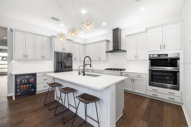 kitchen with white cabinetry, beverage cooler, wall chimney exhaust hood, and appliances with stainless steel finishes