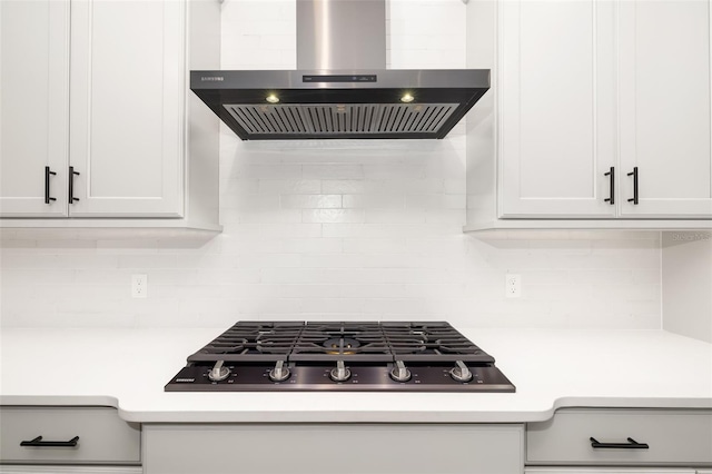 kitchen with stainless steel gas stovetop, white cabinetry, decorative backsplash, and wall chimney exhaust hood