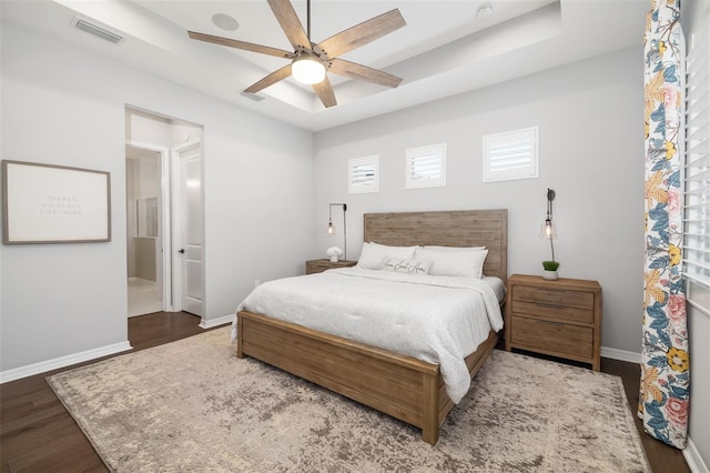 bedroom featuring dark wood-type flooring, ceiling fan, and a raised ceiling