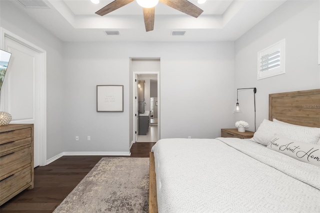 bedroom featuring dark hardwood / wood-style floors, a raised ceiling, and ceiling fan