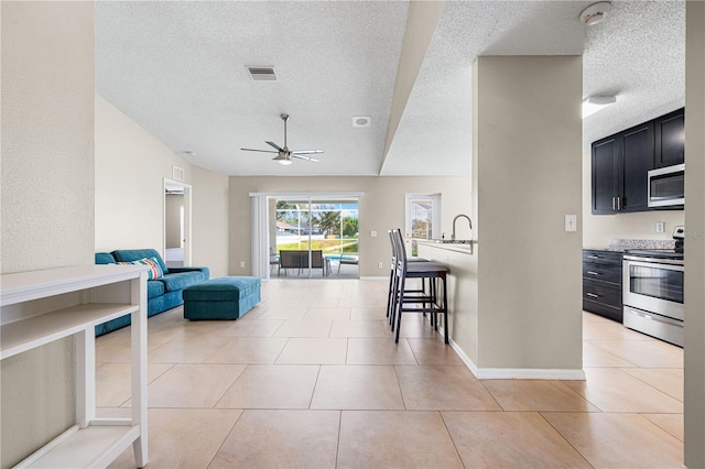 tiled living room with ceiling fan, sink, and a textured ceiling